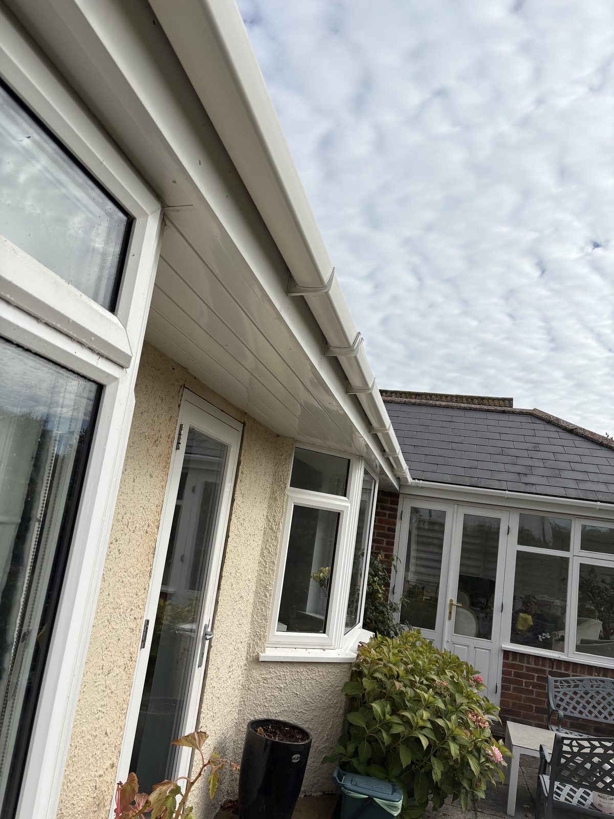 Clean white soffits and fascia along the eaves of a bungalow, looking up at the sky