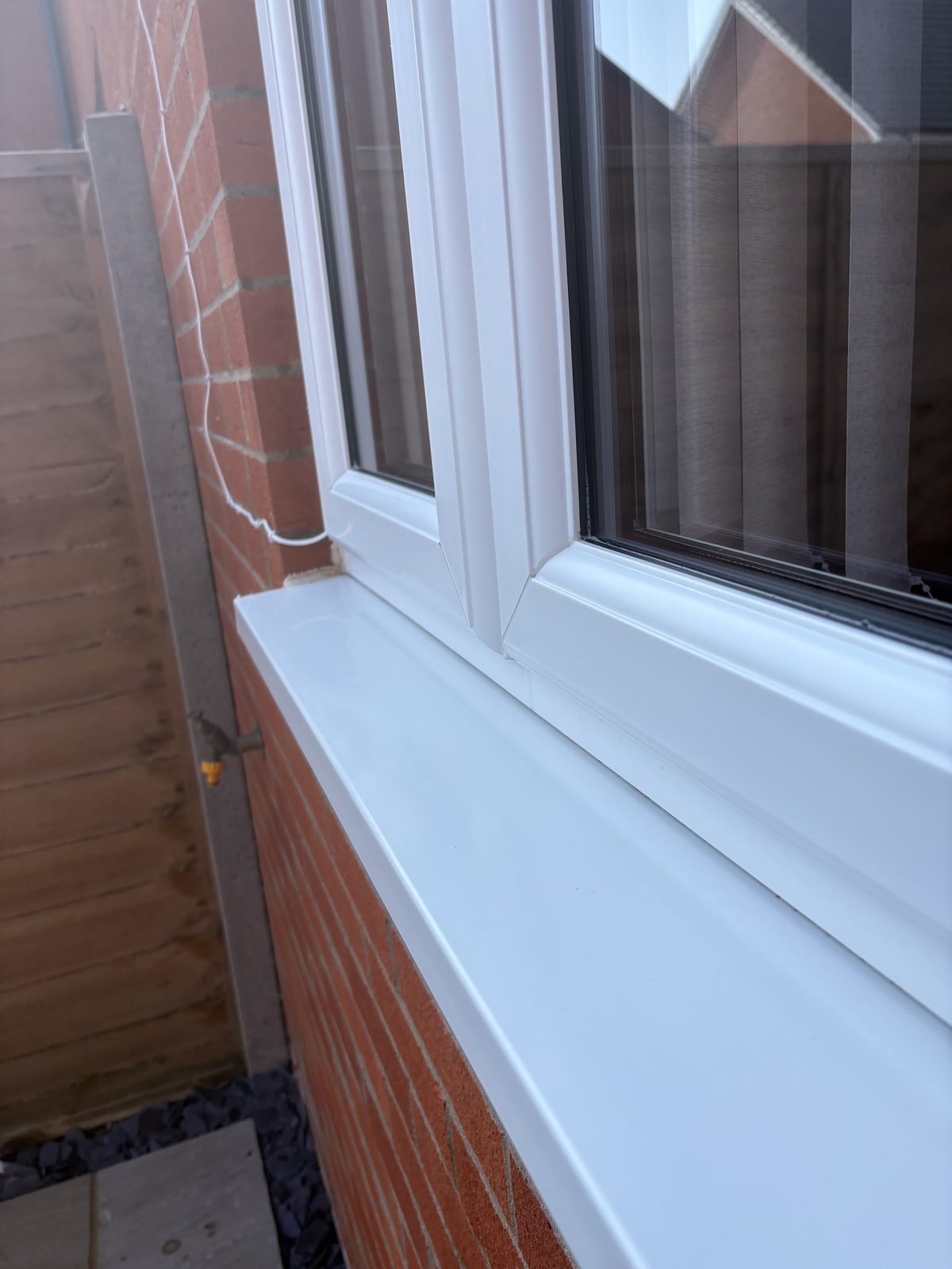 Close-up of a clean white window and sill on a brick wall
