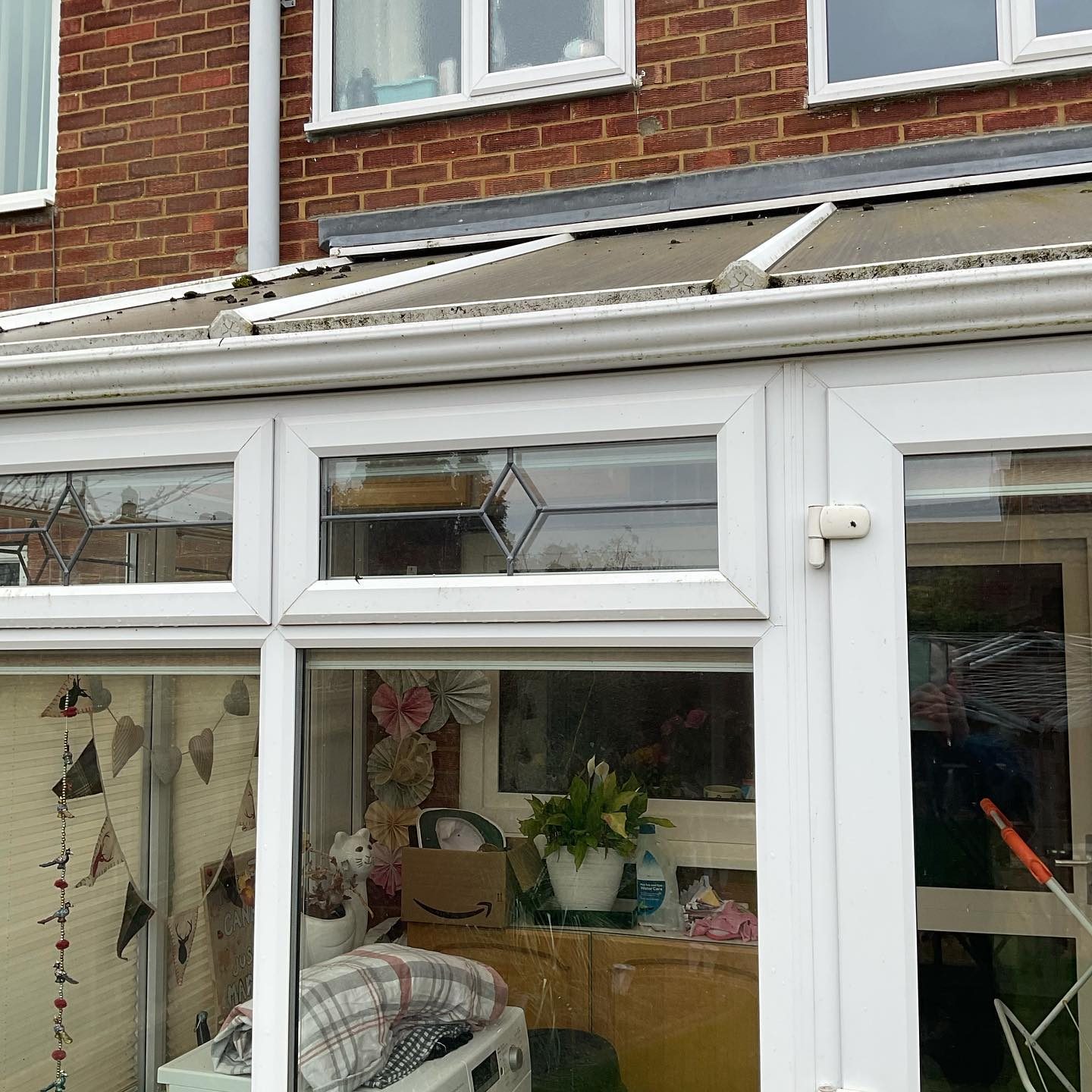 A conservatory with clean glass and white frames, roof panels above