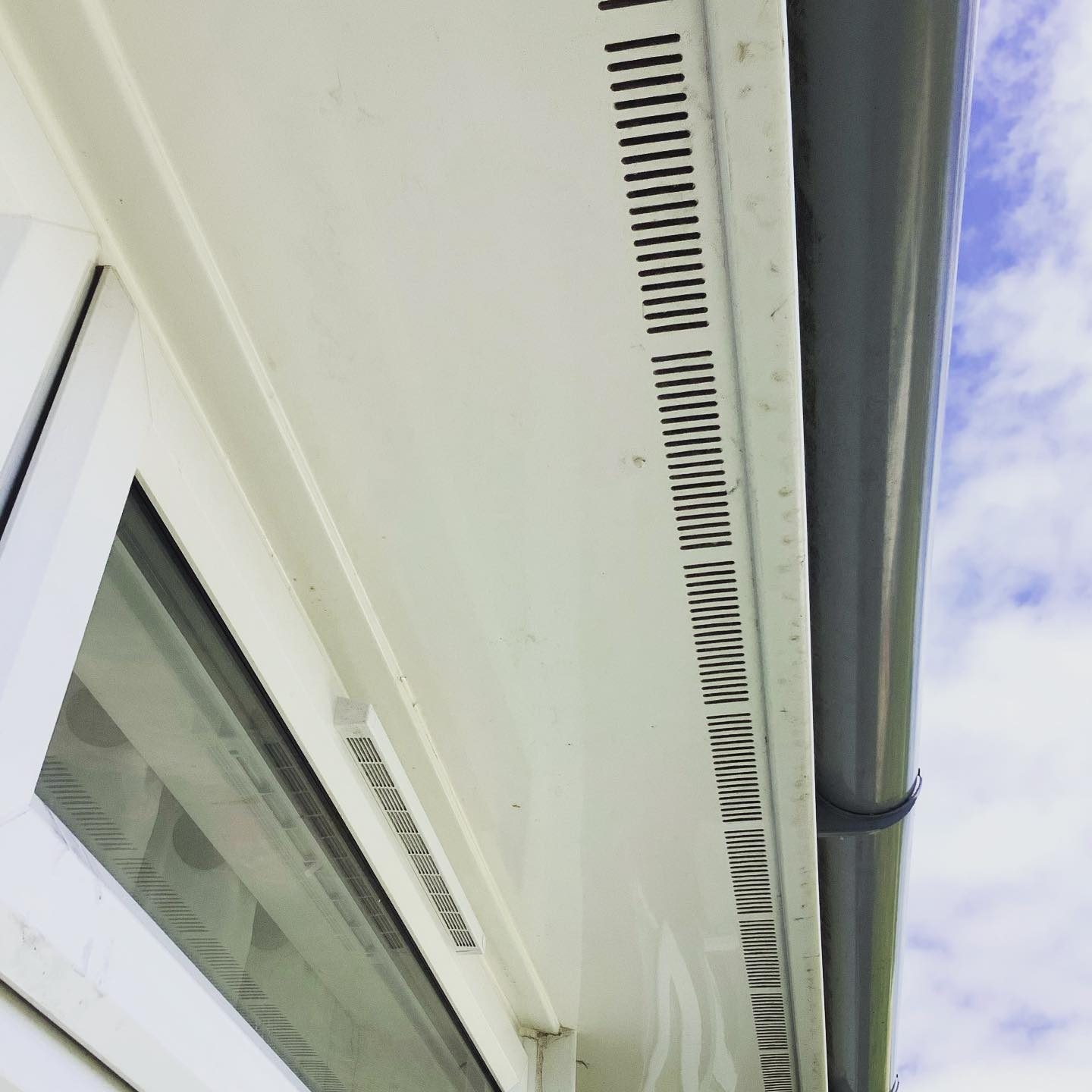 Clean white soffit and fascia boards with vents, a gutter and the top of a window